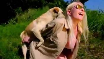 Blonde woman sits naked with the dog licking her snatch